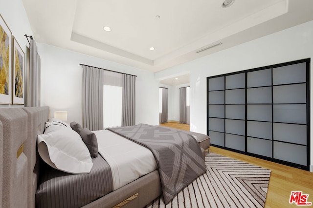 bedroom featuring a tray ceiling and light wood-type flooring