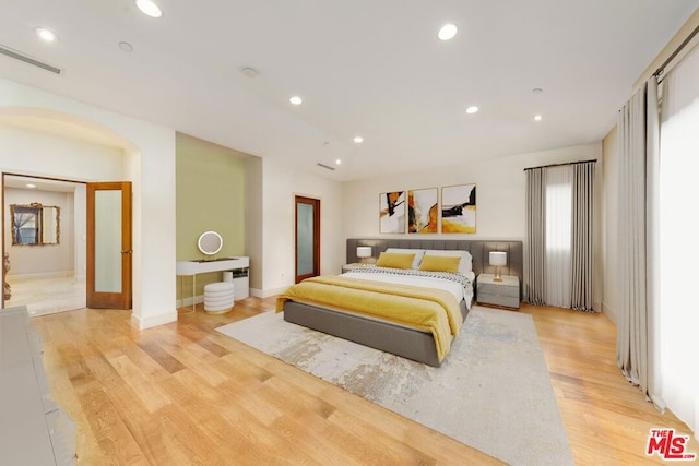 bedroom with connected bathroom and light hardwood / wood-style flooring