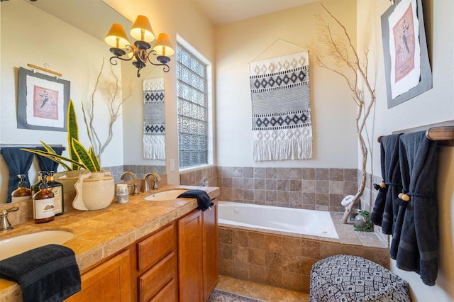 bathroom featuring tiled tub, vanity, and a notable chandelier