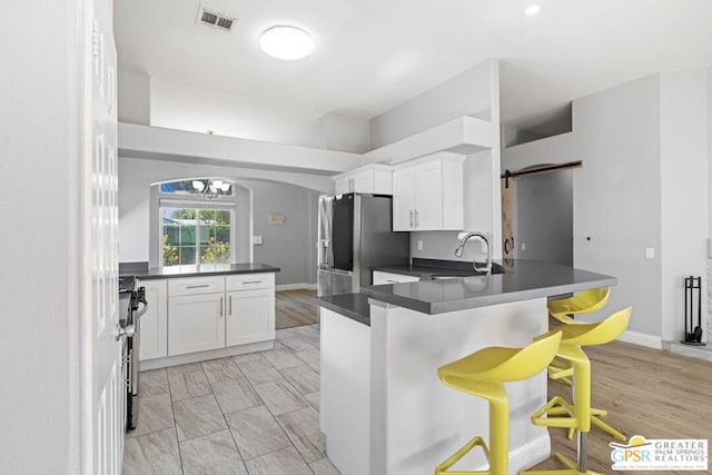 kitchen featuring white cabinetry, kitchen peninsula, a breakfast bar area, stainless steel appliances, and sink