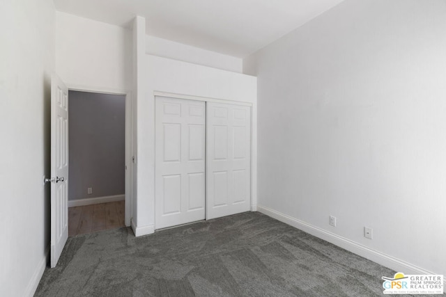 unfurnished bedroom featuring a closet and dark carpet