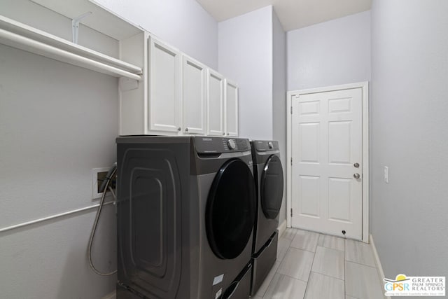 clothes washing area with washing machine and clothes dryer and cabinets