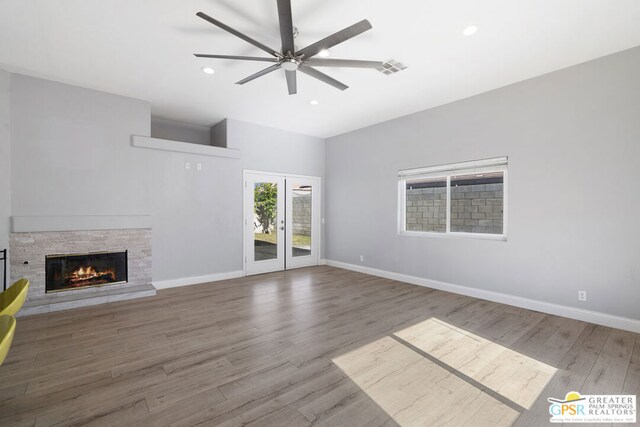 unfurnished living room featuring ceiling fan, wood-type flooring, french doors, and a fireplace