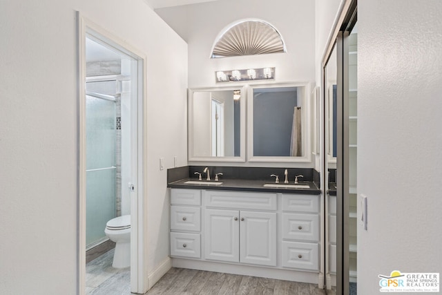 bathroom featuring wood-type flooring, toilet, walk in shower, and vanity