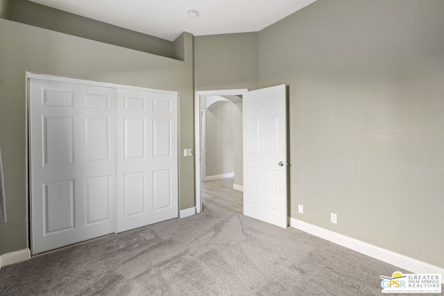 unfurnished bedroom with a closet, light colored carpet, and a high ceiling