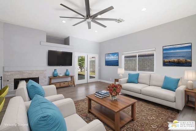 living room featuring ceiling fan, french doors, dark hardwood / wood-style flooring, and a stone fireplace