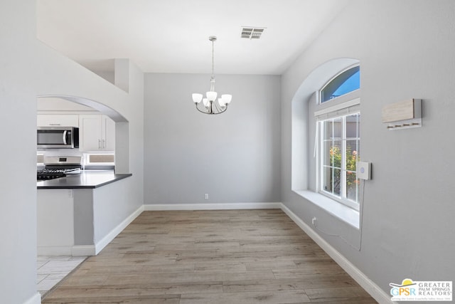 unfurnished dining area featuring light hardwood / wood-style flooring and a chandelier