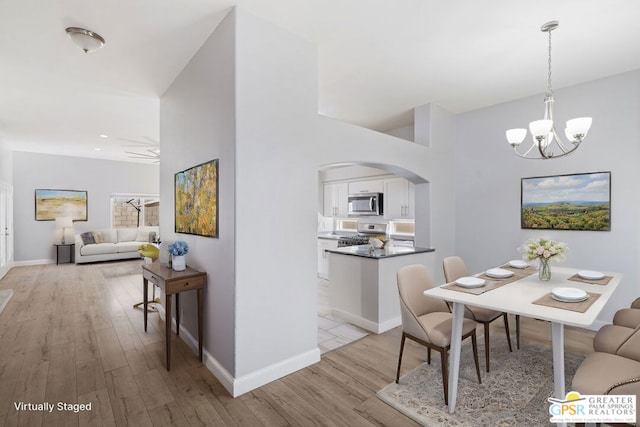 dining area featuring ceiling fan with notable chandelier and light hardwood / wood-style flooring