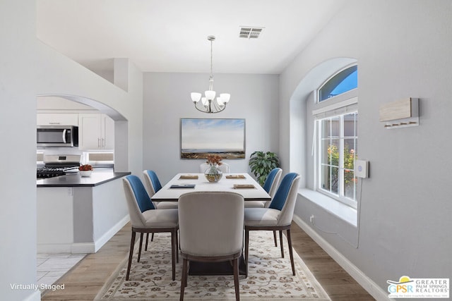 dining room with light hardwood / wood-style floors and an inviting chandelier