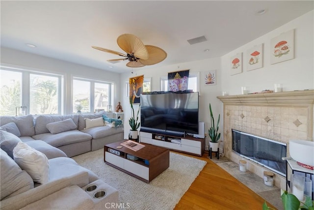 living room with ceiling fan, light wood-type flooring, and a fireplace