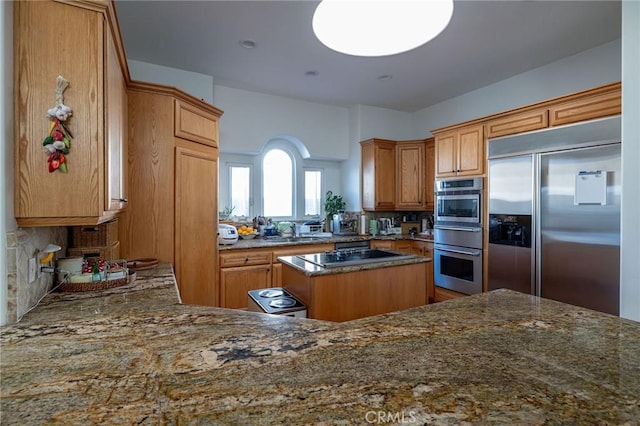 kitchen with decorative backsplash, stainless steel appliances, dark stone counters, and a kitchen island