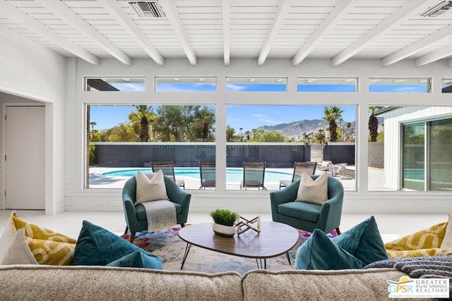 sunroom featuring a mountain view and beam ceiling