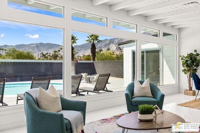 sunroom with a mountain view, a healthy amount of sunlight, and beam ceiling