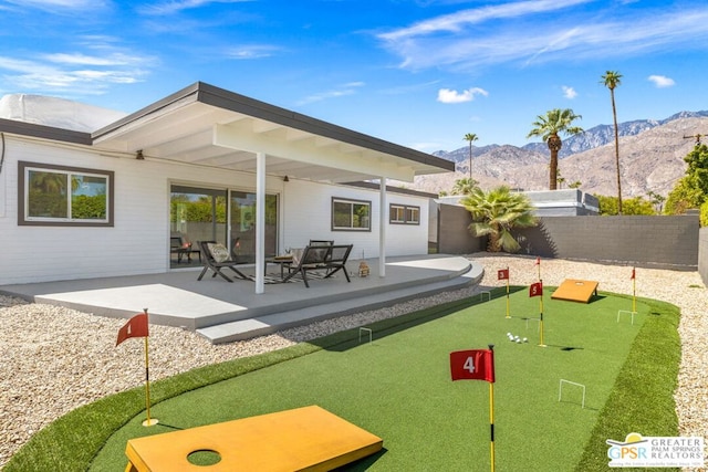 back of property with a mountain view and a patio area