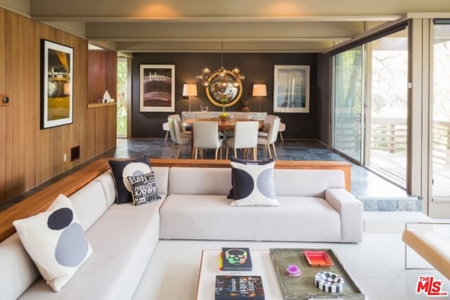 living room with floor to ceiling windows, an inviting chandelier, and wooden walls