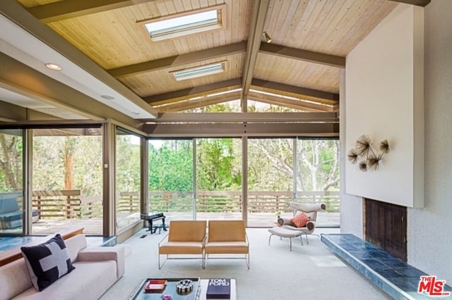 sunroom / solarium featuring a fireplace, lofted ceiling with skylight, and wood ceiling