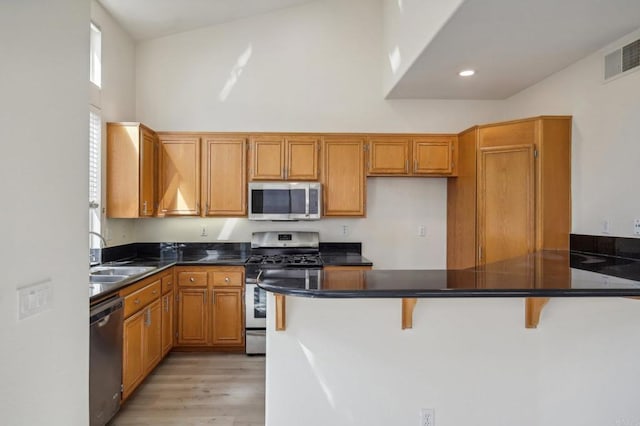 kitchen featuring a wealth of natural light, stainless steel appliances, sink, kitchen peninsula, and a breakfast bar