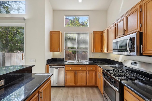 kitchen featuring stainless steel appliances, a healthy amount of sunlight, dark stone counters, and sink