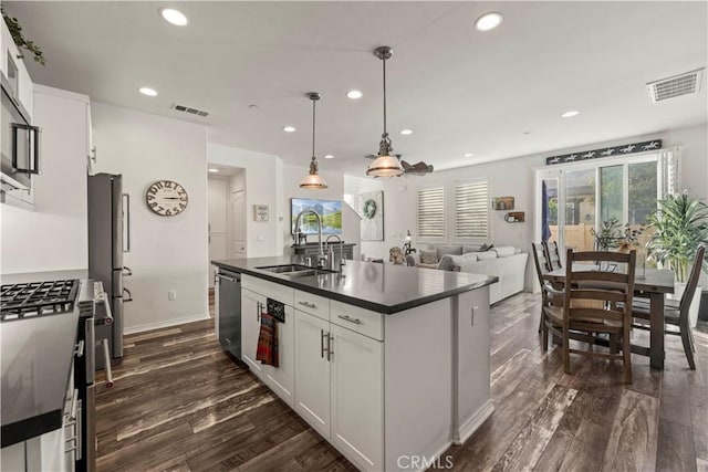 kitchen with decorative light fixtures, sink, white cabinetry, an island with sink, and stainless steel appliances