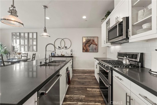 kitchen featuring pendant lighting, decorative backsplash, sink, stainless steel appliances, and white cabinets