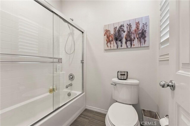 bathroom featuring combined bath / shower with glass door and toilet