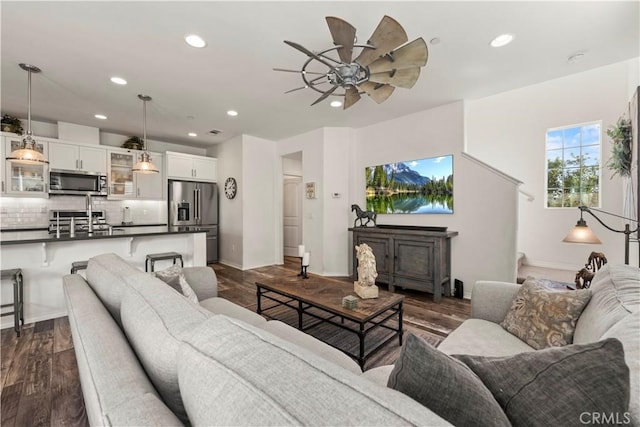 living room featuring dark wood-type flooring, ceiling fan, and sink