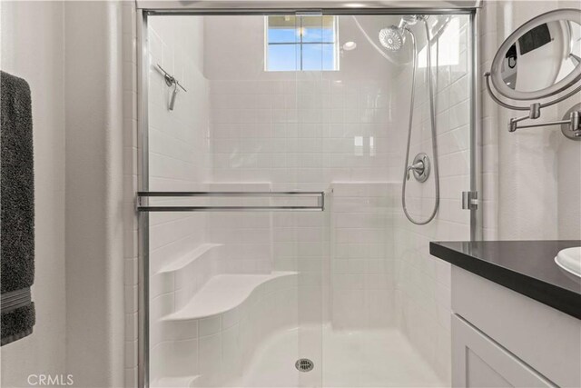 bathroom with a shower with shower door and vanity