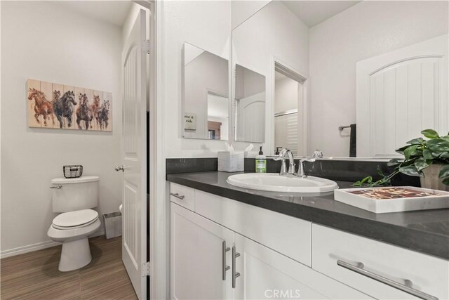 bathroom with hardwood / wood-style floors, toilet, and vanity