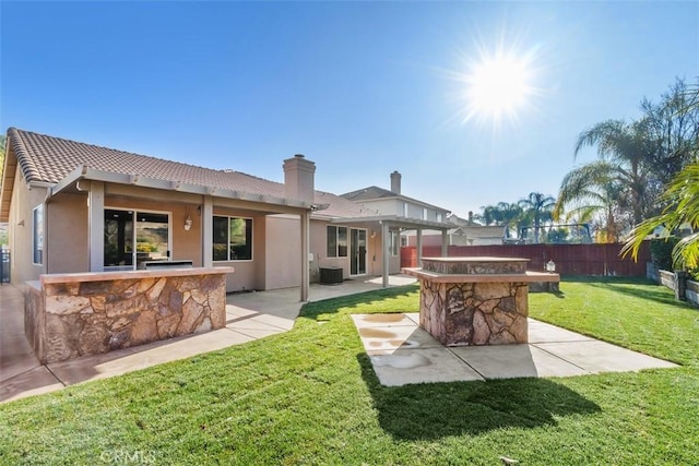 back of house with a lawn, a patio, and exterior bar