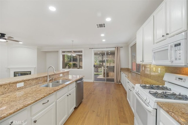 kitchen featuring sink, light hardwood / wood-style flooring, hanging light fixtures, white appliances, and white cabinets