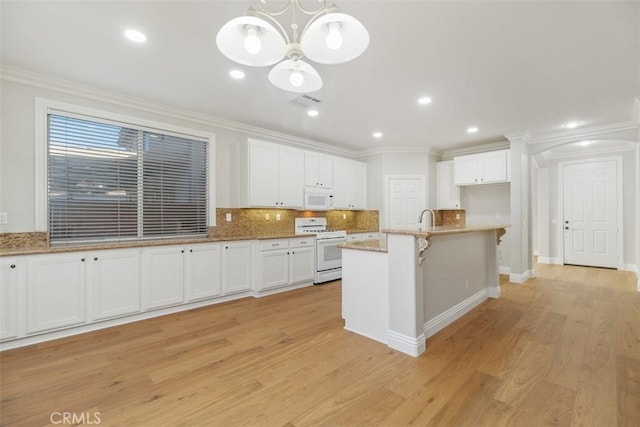 kitchen featuring decorative light fixtures, white cabinetry, ornamental molding, a kitchen island with sink, and white appliances