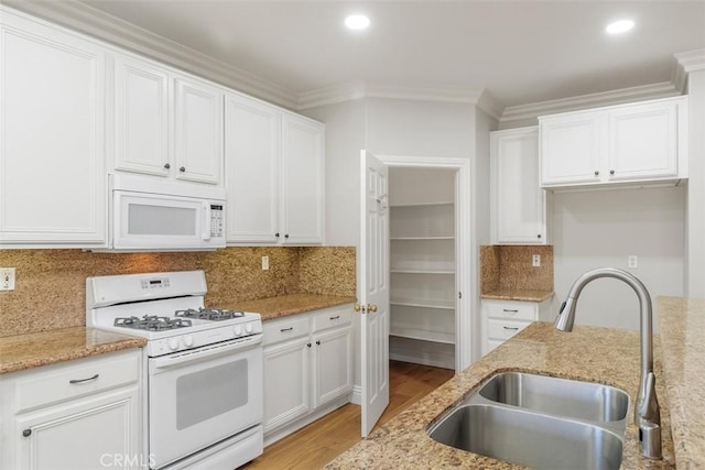 kitchen featuring light stone counters, white appliances, white cabinetry, and sink