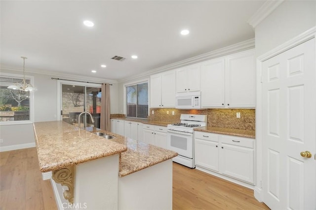 kitchen with sink, white appliances, white cabinets, and a center island with sink