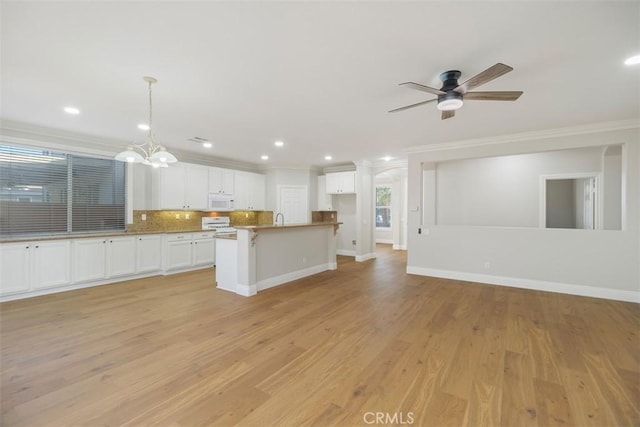 kitchen featuring pendant lighting, crown molding, a center island, white cabinets, and decorative backsplash