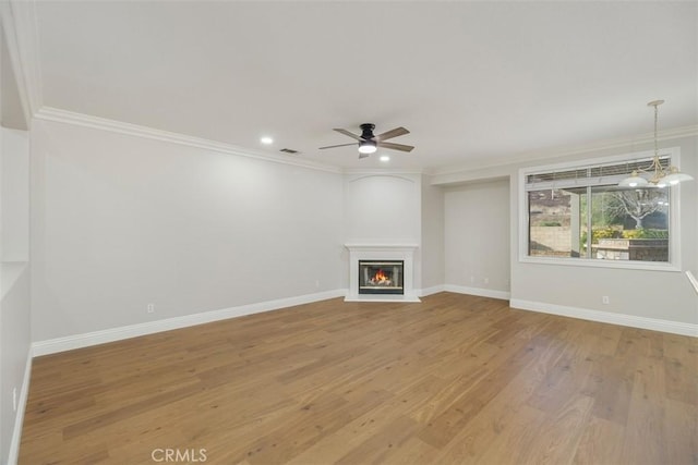 unfurnished living room with hardwood / wood-style flooring, ornamental molding, and ceiling fan with notable chandelier