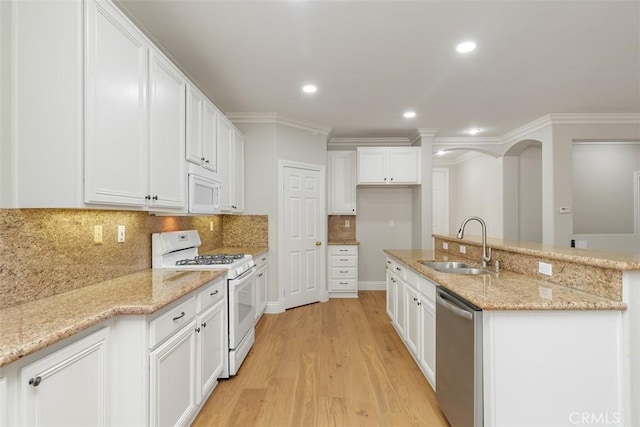 kitchen with light stone counters, white appliances, sink, and light hardwood / wood-style flooring