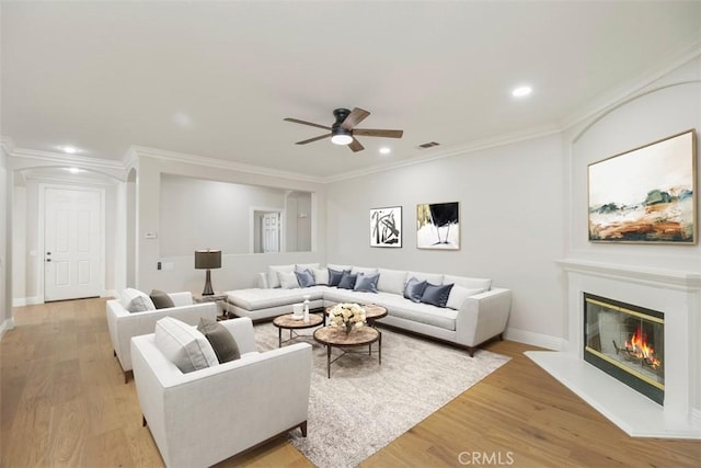 living room with ornamental molding, light hardwood / wood-style floors, and ceiling fan