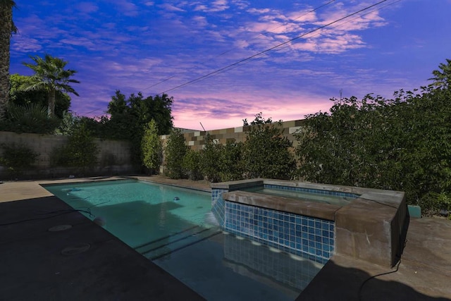 pool at dusk with an in ground hot tub