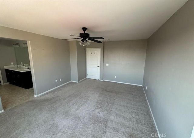 unfurnished bedroom with ensuite bathroom, carpet flooring, sink, and ceiling fan