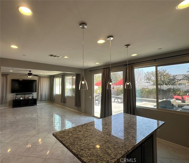 kitchen featuring stone counters, light tile patterned flooring, plenty of natural light, and decorative light fixtures