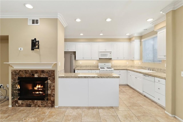 kitchen featuring light stone countertops, a fireplace, ornamental molding, white appliances, and white cabinets