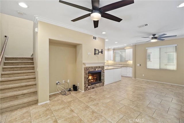 unfurnished living room featuring light tile patterned floors, ceiling fan, ornamental molding, and a premium fireplace