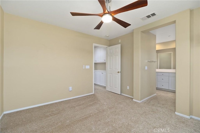 unfurnished bedroom featuring ceiling fan, ensuite bathroom, and light colored carpet