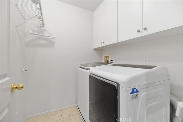 laundry area with cabinets, light tile patterned floors, and washing machine and clothes dryer