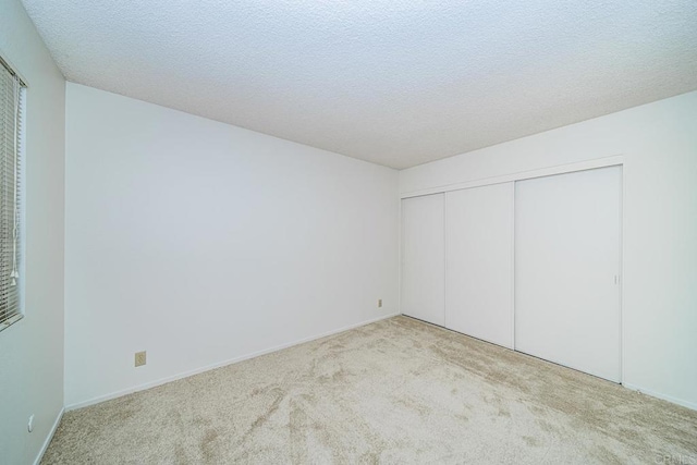 unfurnished bedroom with a textured ceiling, a closet, and light carpet