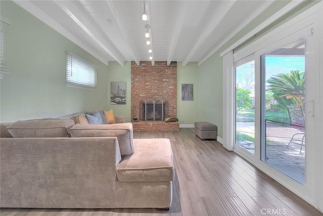 living area with light wood-type flooring, plenty of natural light, a fireplace, and beam ceiling