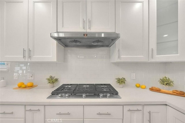 kitchen featuring light countertops, stainless steel gas stovetop, glass insert cabinets, white cabinets, and exhaust hood