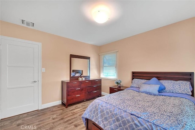 bedroom with baseboards, visible vents, and light wood finished floors