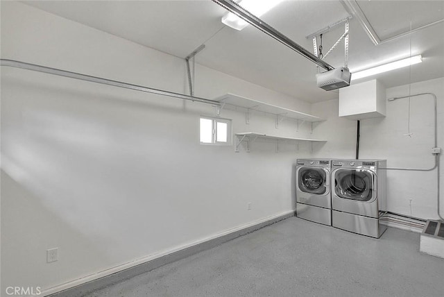 clothes washing area with a garage, laundry area, attic access, baseboards, and washing machine and dryer