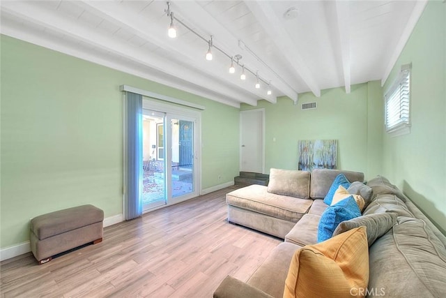 living area featuring beam ceiling, visible vents, and baseboards